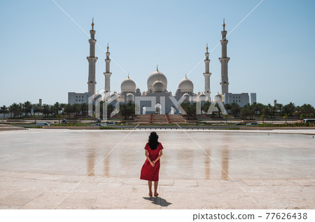 Woman enjoying view of Sheikh Zayed Grand Mosque in Abu Dhabi, United Arab Emirates on a sunny day 77626438