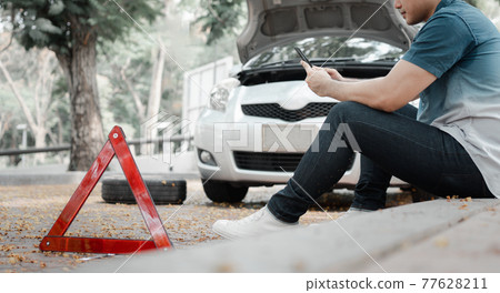 Asian man using smartphone for assistance after a car breakdown on street. Concept of vehicle engine problem or accident and emergency help from Professional mechanic Asian man using smartphone for assistance after a car breakdown on street. Concept of vehicle engine problem or accident and emergency help from Professional mechanic 77628211