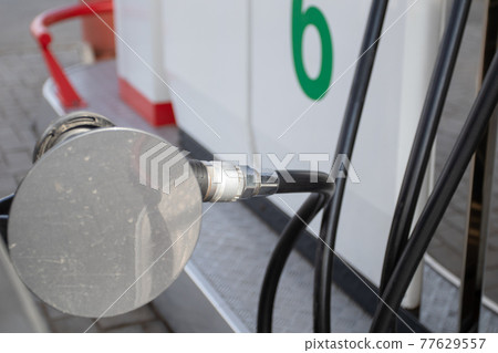 An automobile is getting refueled by a petrol pistol. 77629557