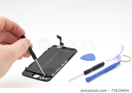 An engineer repairing the display on the smartphone. Hands holding screwdriver. An engineer repairing the display on the smartphone. Hands holding screwdriver. 77629604
