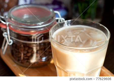 Cappuccino in a double glass cup and jar with coffee beans on wooden plate Cappuccino in a double glass cup and jar with coffee beans on wooden plate 77629606