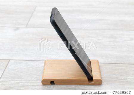 Black smartphone on a wooden stand Black smartphone on a wooden stand 77629807