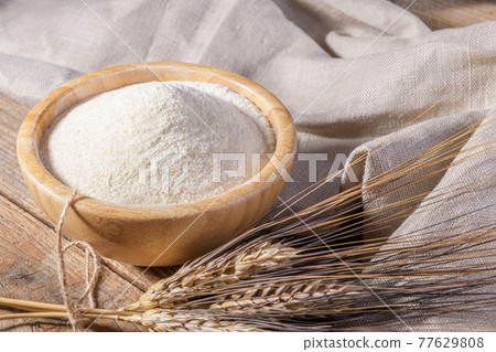 Whole wheat durum flour in wooden bowl with spikelets Whole wheat durum flour in wooden bowl with spikelets 77629808