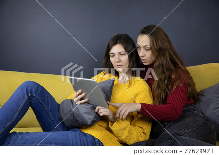 two pretty girls make purchases or payments online using tablet Couch shopping 77629971