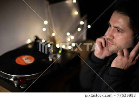 Young unshaven handsome millennial guy focused on music with headphones Young unshaven handsome millennial guy focused on music with headphones 77629988