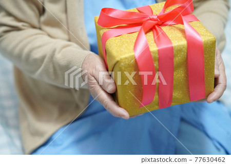 Asian elderly woman opening a gift or present at Christmas. Happy