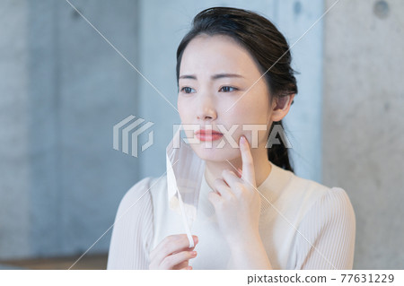 Young woman worries about rough skin due to mask Young woman worries about rough skin due to mask 77631229