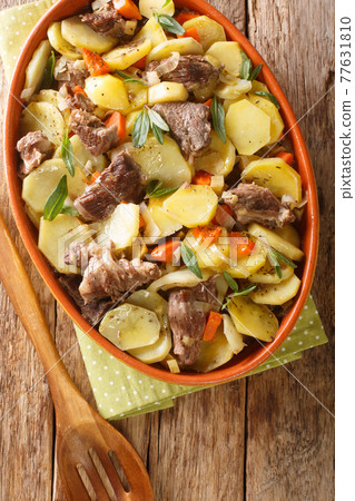 Baeckeoffe is a casserole dish a mix of potatoes, onions, mutton, beef, and pork which have been marinated in Alsatian white wine and juniper berries closeup. Vertical top view Baeckeoffe is a casserole dish a mix of potatoes, onions, mutton, beef, and pork which have been marinated in Alsatian white wine and juniper berries closeup. Vertical top view 77631810