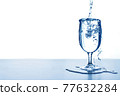 Pour water into a glass 77632284