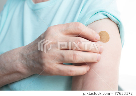 Vaccination elderly woman in doctor office with adhesive covid-19 vaccine plaster. 77633172
