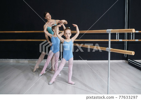the teacher helps the girls to do the exercises correctly. classes at the choreographic school. 77633297