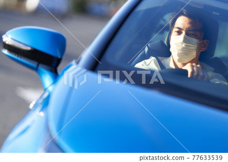 Young man driving a car wearing a mask 77633539