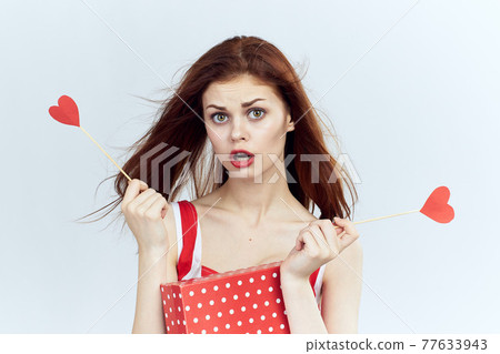 Pretty woman holding a gift in her hands holiday red lips light background 77633943