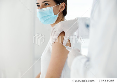 doctor in protective gloves injects a vaccine into the shoulder of a woman patient covid vaccination doctor in protective gloves injects a vaccine into the shoulder of a woman patient covid vaccination 77633966