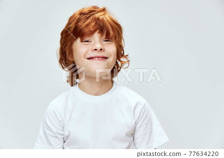 Smiling redhead boy looking forward cropped view of white t-shirt 77634220