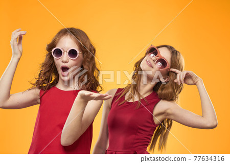 Two sisters and fun sunglasses fashion Friendship yellow background family Two sisters and fun sunglasses fashion Friendship yellow background family 77634316
