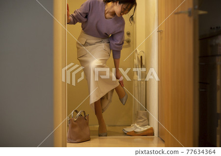 一個女人回家在門口脫鞋 77634364