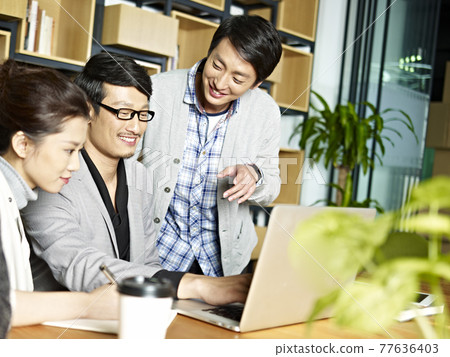 a team of young asian business people working together using laptop computer in office 77636403