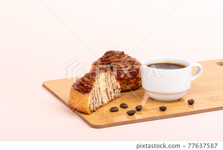 White cup with black coffee and cinnamon rolls on a cutting board. White cup with black coffee and cinnamon rolls on a cutting board. 77637587