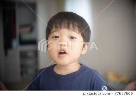 A 3-year-old child talking in the living room of an apartment 77637609
