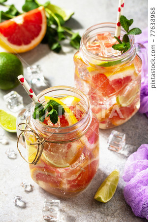 Ice refreshing drink. Mason jar mug filled with Fresh mojito cocktail with grapefruit, lime and mint on a background of gray stone. 77638968