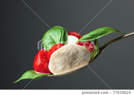 Mozzarella with tomato and basil on a dark background. 77639024