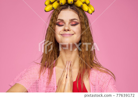 Woman with bananas wavy hair fruits lifestyle bright makeup pink background 77639172