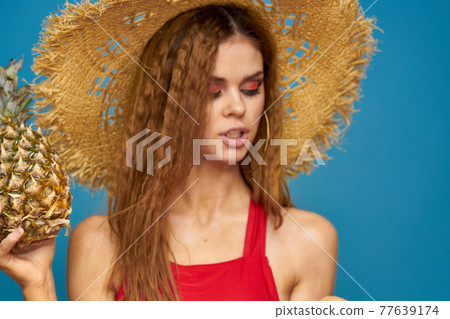 Woman in a straw hat with pineapple in her hands wavy hair exotic fruits you summer blue background vacation Woman in a straw hat with pineapple in her hands wavy hair exotic fruits you summer blue background vacation 77639174