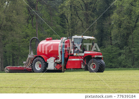 Injecting a freshly mowed lawn with a red injector . Injecting a freshly mowed lawn with a red injector . 77639184