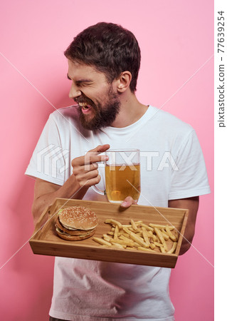 Man with tray of fast food and mug of beer french fries fast food cropped view 77639254