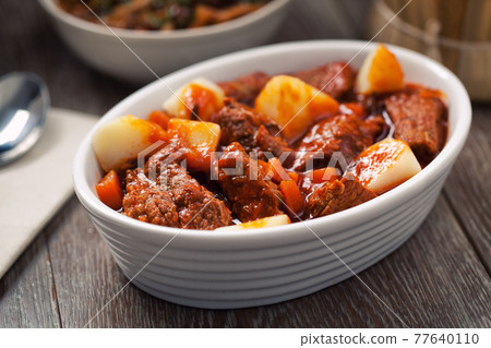 Hot stew with mushrooms and potatoes on a plate. 77640110