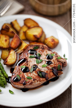 Fillet of beef with potatoes and asparagus on a plate. Fillet of beef with potatoes and asparagus on a plate. 77640191