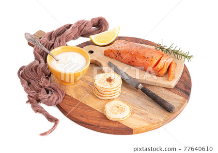 Artisanal smoked salmon on a cutting board with blinis and cream Artisanal smoked salmon on a cutting board with blinis and cream 77640610