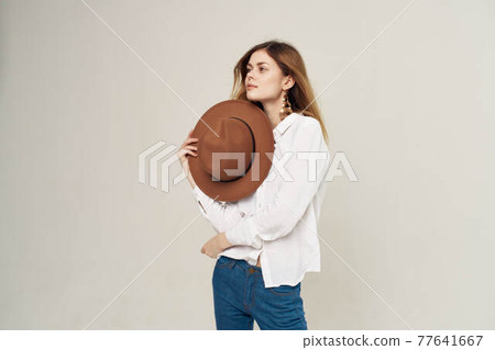 Pretty woman holding hat in her hand white shirt fashion lifestyle beige background 77641667
