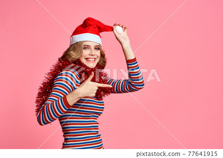Woman with tinsel around her neck and with a cap on her head on a pink background cropped view 77641915