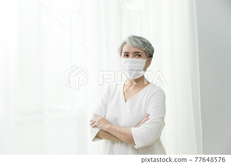站在落地窗前脫戴口罩的婦女 77648576