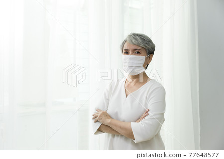 站在落地窗前脫戴口罩的婦女 77648577