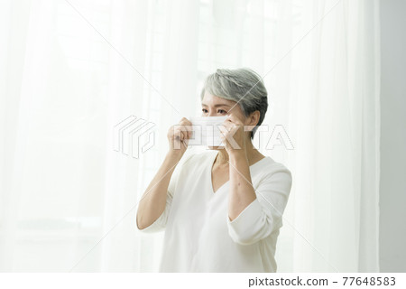 站在落地窗前脫戴口罩的婦女 77648583