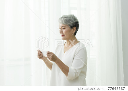 站在落地窗前脫戴口罩的婦女 77648587