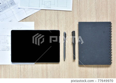 a top view of architect working desk with equipment drawings pens notebook sketched idea on wood table, the concept of modern technology for architectural working with tablet 77649970