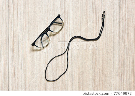 Clear eyeglasses, Glasses transparent dark blue frame with black eyeglasses strap make shape like sperm on a wooden background, a concept of aging with sexual performance Clear eyeglasses, Glasses transparent dark blue frame with black eyeglasses strap make shape like sperm on a wooden background, a concept of aging with sexual performance 77649972