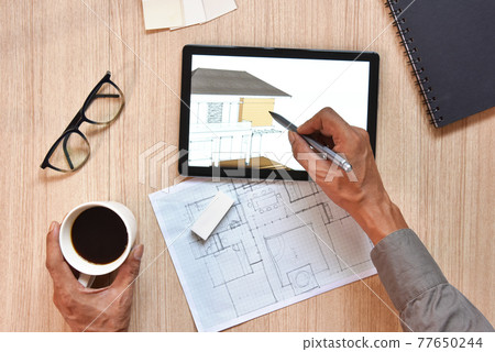 a top view of architect working desk with hand writing and draw on equipments for drawings pens sketched idea on wood table, the concept of modern technology for architectural working with tablet 77650244