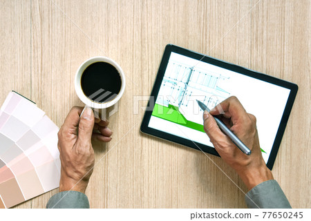 a top view of architect working desk with hand writing and draw on equipment for drawings pens sketched idea on wood table, the concept of modern technology for architectural working with tablet a top view of architect working desk with hand writing and draw on equipment for drawings pens sketched idea on wood table, the concept of modern technology for architectural working with tablet 77650245