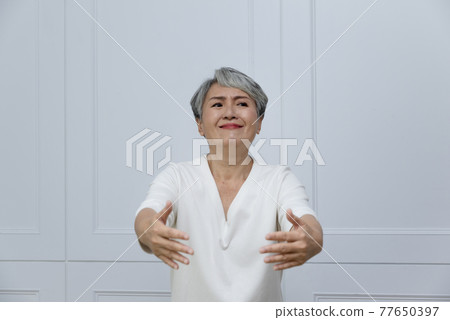 An elderly woman with silver hair next to the floor-to-ceiling window An elderly woman with silver hair next to the floor-to-ceiling window 77650397