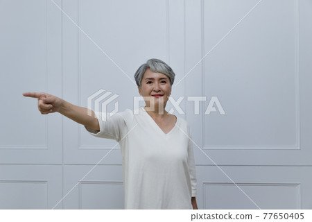 An elderly woman with silver hair next to the floor-to-ceiling window An elderly woman with silver hair next to the floor-to-ceiling window 77650405