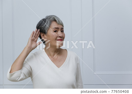一位銀髮白髮的年長婦女在落地窗旁 一位銀髮白髮的年長婦女在落地窗旁 77650408