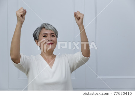 一位銀髮白髮的年長婦女在落地窗旁 77650410