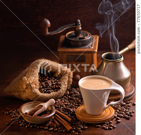 cup of coffee and coffee beans in a sack on dark background, top view cup of coffee and coffee beans in a sack on dark background, top view 77650717
