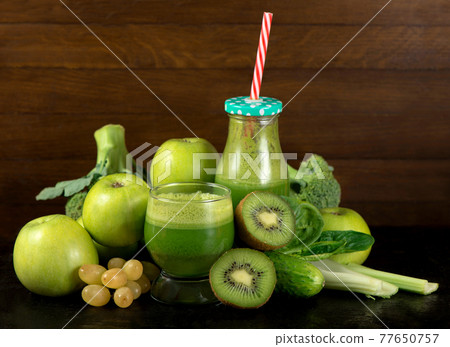 Green vegetable smoothie in jars and ingredients on the white wooden background. Diet concept with text space. Green vegetable smoothie in jars and ingredients on the white wooden background. Diet concept with text space. 77650757