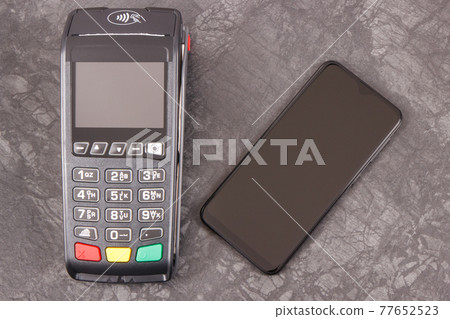 Hand of woman using payment terminal and smartphone to cashless paying. Finance concept Hand of woman using payment terminal and smartphone to cashless paying. Finance concept 77652523